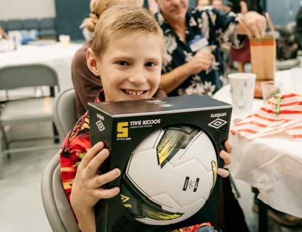 Young boy proudly showing the camera his gift of a soccer ball